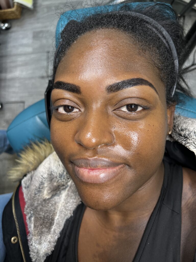 Dark skinned black woman shows off her bold arched Custom Brow & Henna Design by Bare Fruit Sugaring