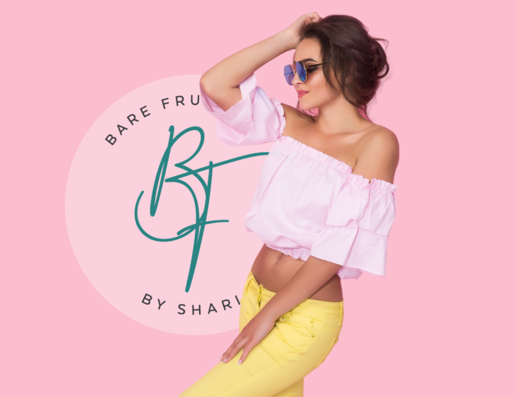 Slender model in glasses and a crop top and lowcut yellow jeans poses before the Bare Fruit By Shari Saint logo.